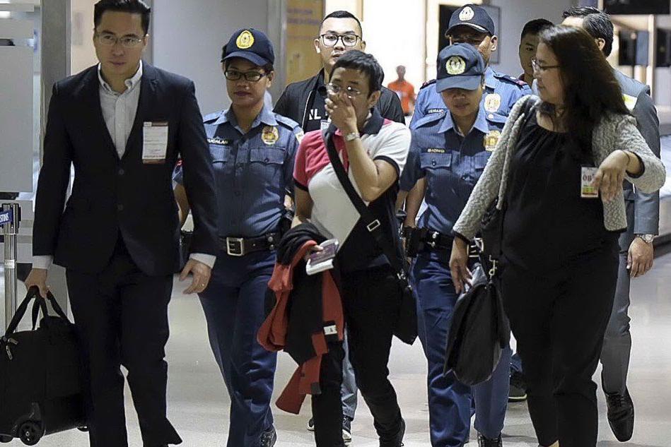 La giornalista scortata dai poliziotti all'aeroporto di Manila (Ansa)