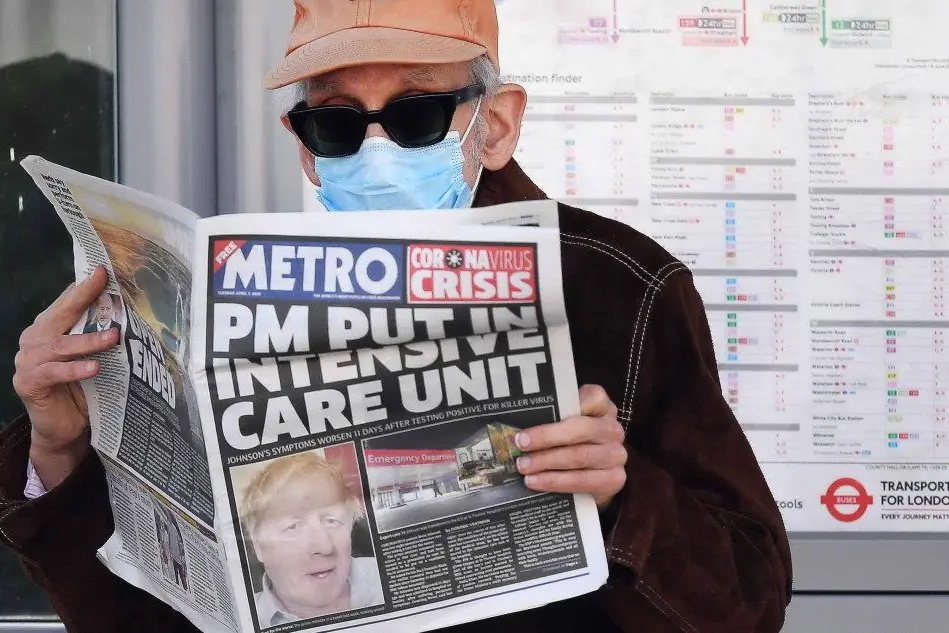 Londra, un uomo legge il tabloid che parla delle condizioni del premier (Ansa)