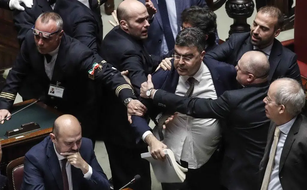 Emanuele Fiano (Pd) cerca di raggiungere i banchi della presidenza, trattenuto dai commessi