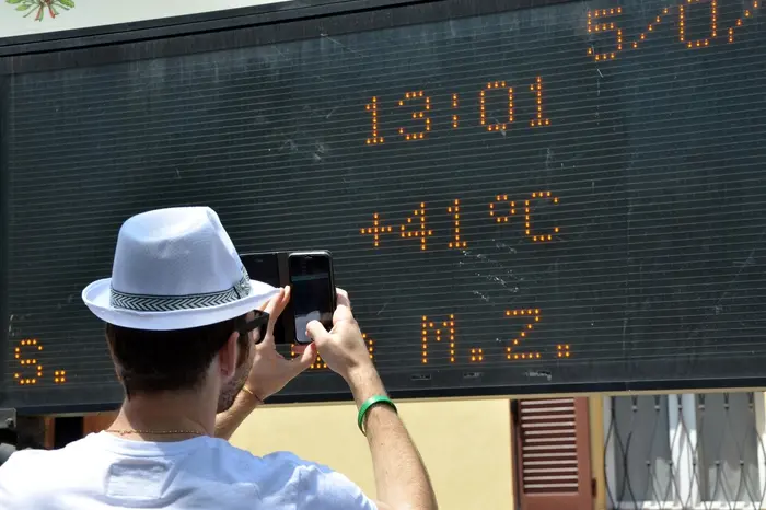 Un ragazzo fotografa un tabellone elettronico che segna 41 gradi a Pozzolo Formigaro (Alessandria), 5 luglio 2015. ANSA/ DINO FERRETTI