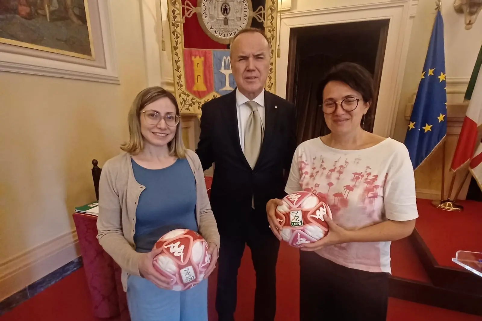 Mauro Balata, presidente della Lega B, omaggia due dipendenti dell’Università di Sassari col pallone rosso simbolo del contrasto alla violenza sulle donne (foto concessa)
