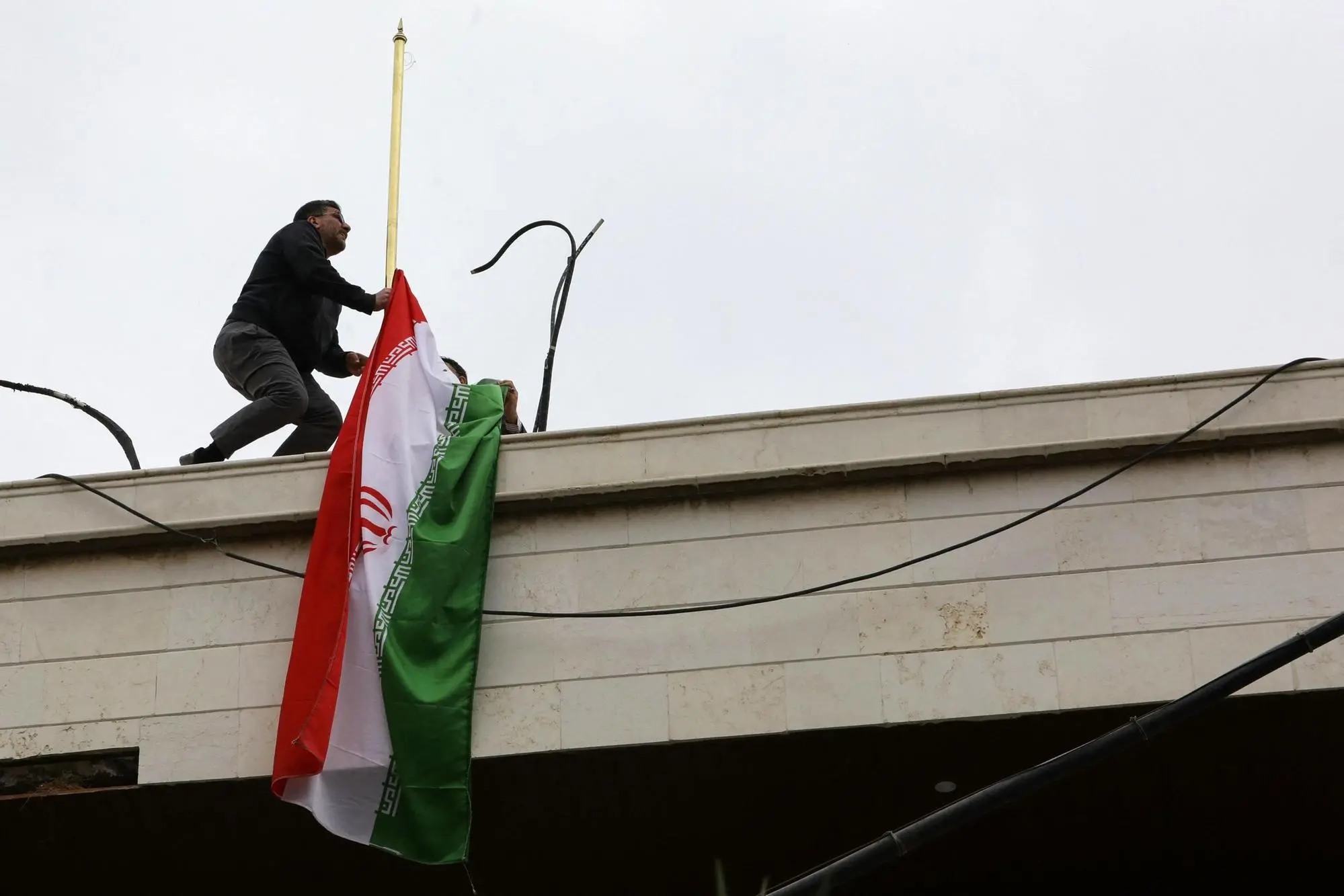 La bandiera iraniana collocata sulla sede diplomatica a Damasco (Afp via Ansa)
