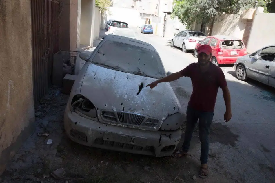 Tripoli, un uomo mostra la sua auto crivellata (foto Ansa)
