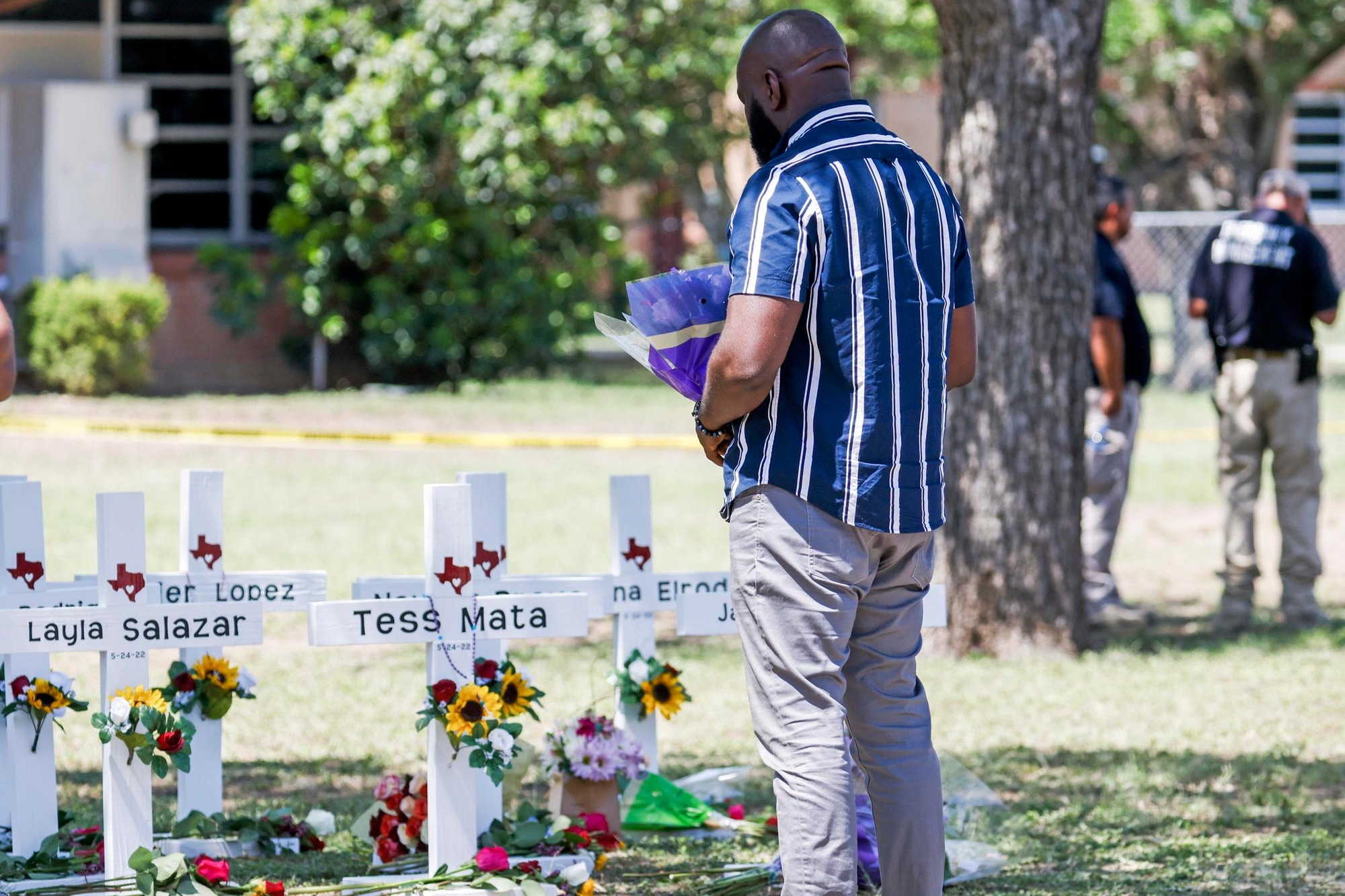 epa09978090 A man holds flowers as he views crosses bearing the names of victims following a mass shooting at the Robb Elementary School in Uvalde, Texas, USA, 26 May 2022. According to Texas officials, at least 19 children and two adults were killed in the shooting on 24 May. The eighteen-year-old gunman was killed by responding officers. EPA/TANNEN MAURY