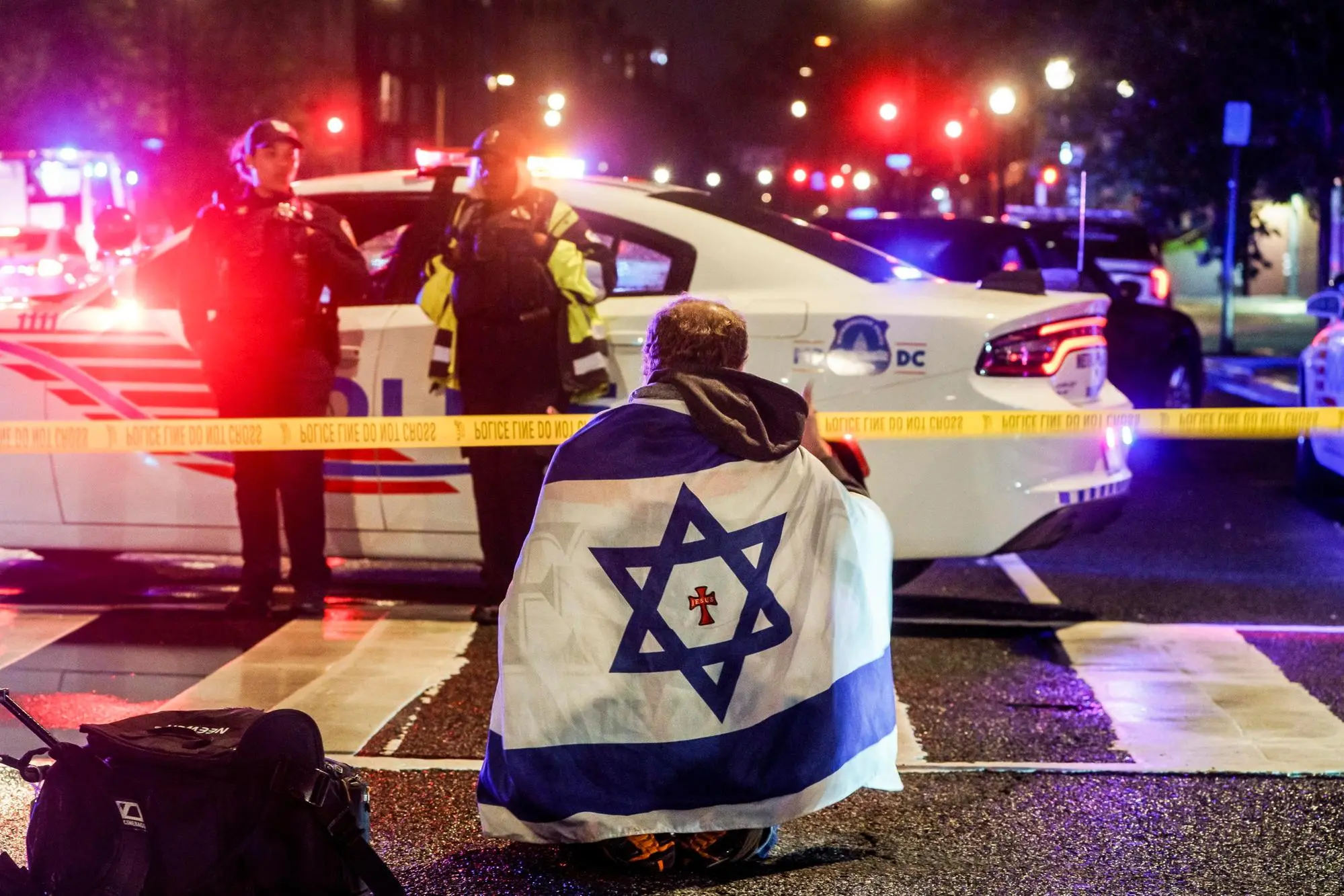epaselect epa12124462 A man with an Israeli flag draped on his shoulders near the scene where two people were shot and killed near the Capital Jewish Museum in Washington, DC, USA, 22 May 2025. According to a social media post by the US Homeland Security Secretary Kristi L. Noem, the two people killed were staff members at the Israeli embassy. EPA/WILL OLIVER