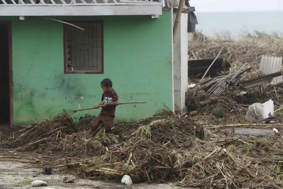 Un bimbo in una zona devastata dallo tsunami (Ansa)