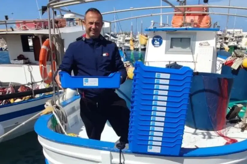 Un pescatore di Porto Torres con le nuove cassette per il pesce riutilizzabili (foto L'Unione Sarda - Tellini)