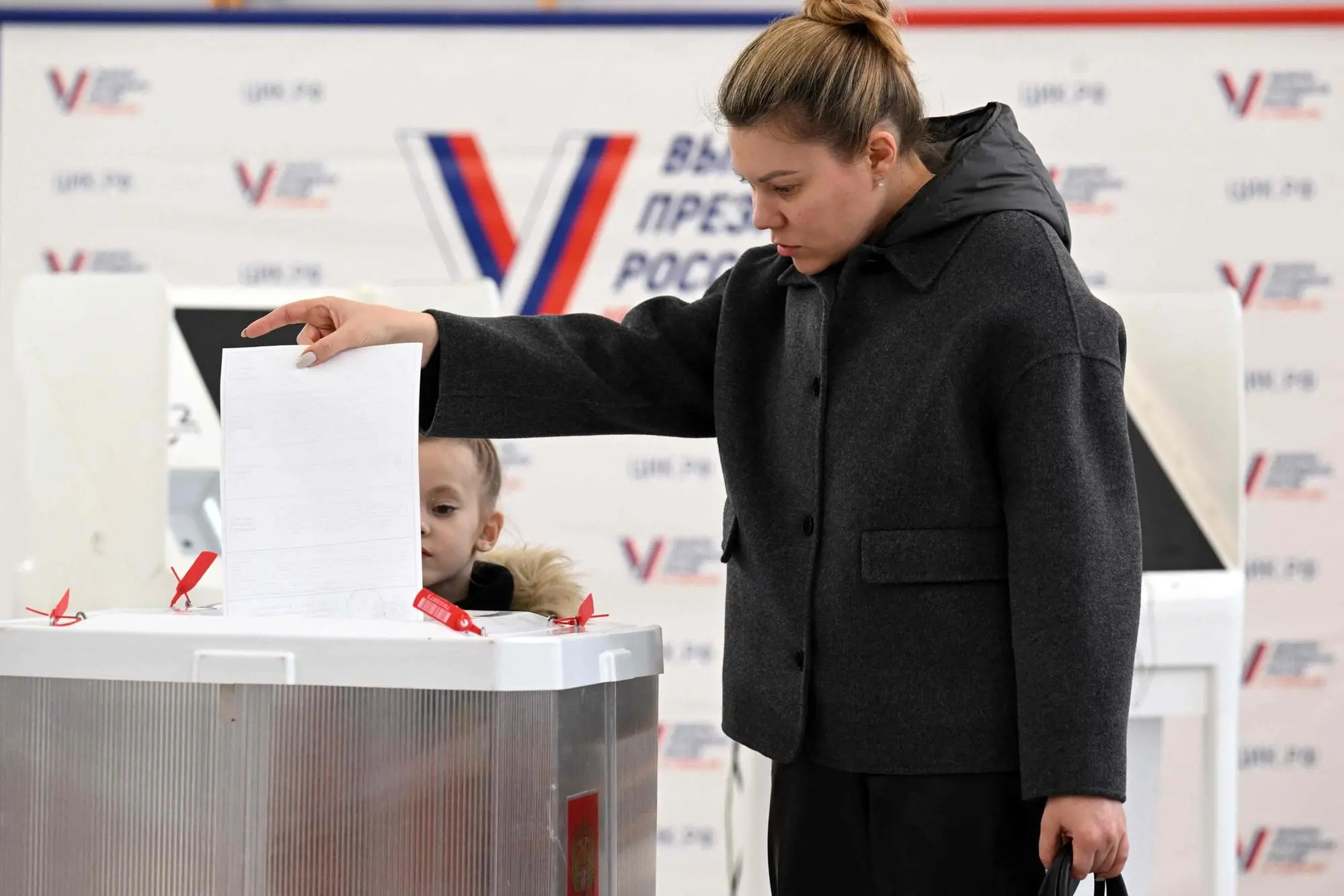A woman with her child votes in Russia's presidential election in Moscow on March 16, 2024. (Photo by NATALIA KOLESNIKOVA / AFP)
