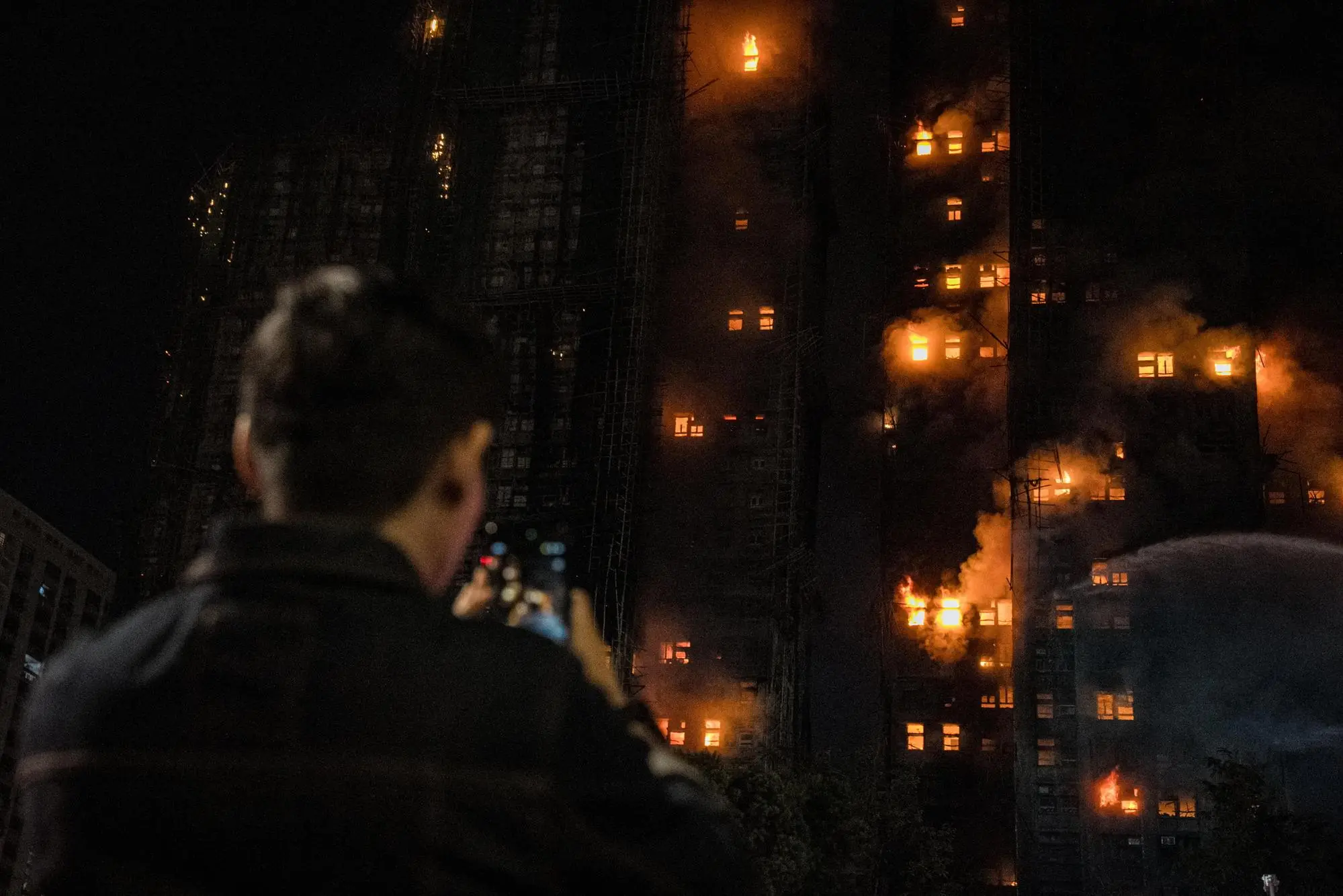 epa12550221 A person photographs an apartment fire in Tai Po in Hong Kong, China, 26 November 2025. According to the Hong Kong government, the five alarm fire, which started 26 November, has left at least 13 people dead and three in critical condition. EPA/LEUNG MAN HEI