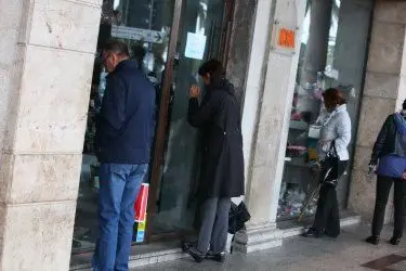 Passanti guardano le vetrine, ma in negozi sono chiusi