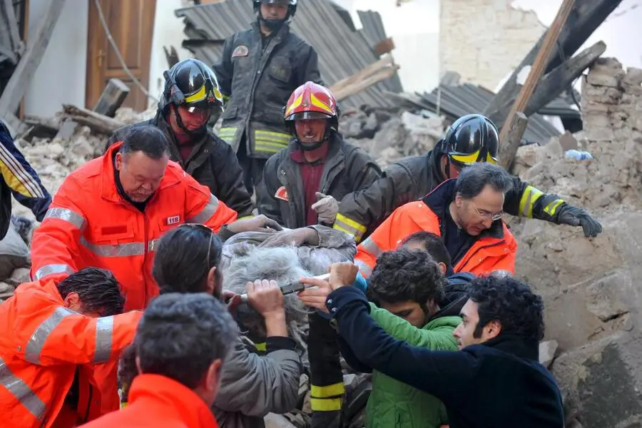 epa01689457 Italian rescue teams retrieve a person from a building which collapsed following an earthquake, in L'aquila, Central Italy, 06 April 2009. At least nine people were killed 06 April in the central Italian region of Abruzzo when a magnitude-5.8 earthquake struck, police said. Five of the dead were from Castelnuovo, where dozens of houses and a church collapsed, they said in their initial toll from the disaster, which did not include four children that Italian media reported had died in a hospital in Lâ??Aquila, Abruzzo's capital. Numerous buildings collapsed in Lâ??Aquila, where people were searching for survivors in the rubble of a house and student dormitory in the cityâ??s historic centre. EPA/PERI - PERCOSSI