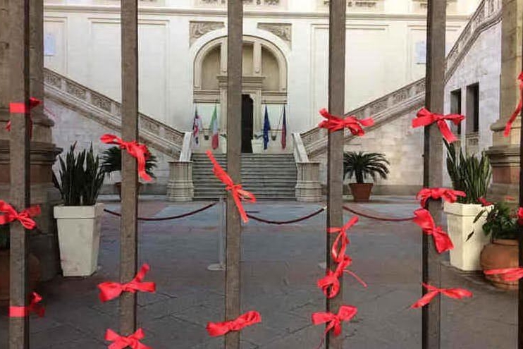 Nastri rossi all'ingresso del Palazzo civico a Cagliari (foto Twitter Comune di Cagliari)