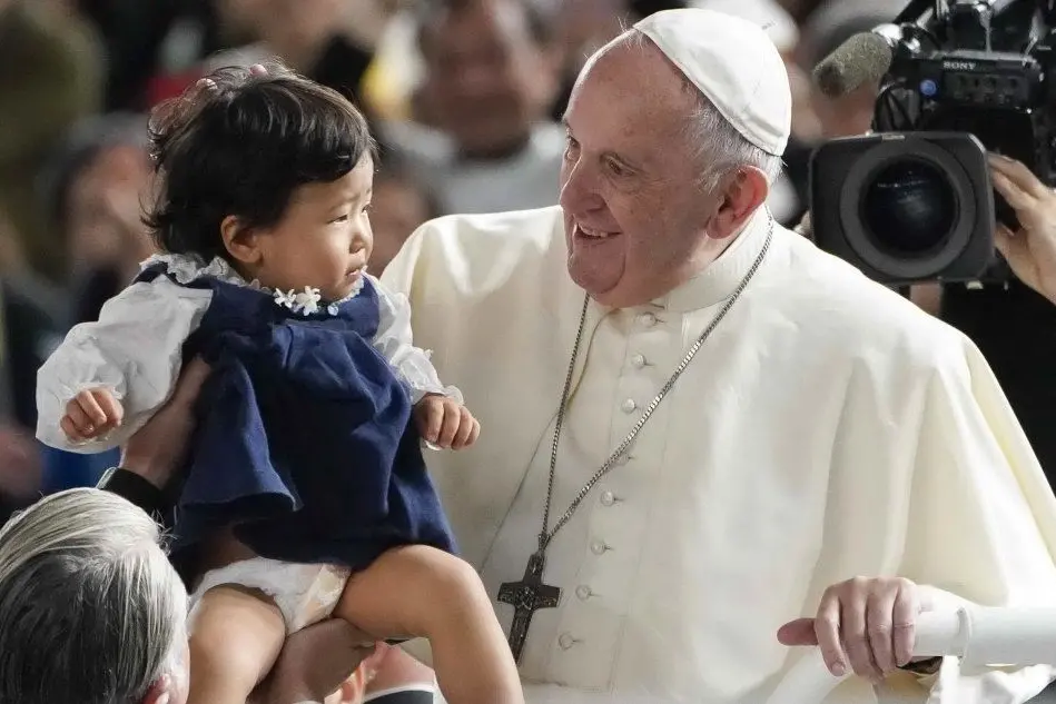 Papa Francesco con un bimbo a Tokyo (Ansa)