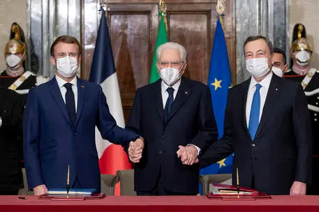 Il president Sergio Mattarella tra il capo di Stato francese Emmanuel Macron e il premier italiano Mario Draghi in occasione della firma del Trattato Italia-Francia (Ansa)