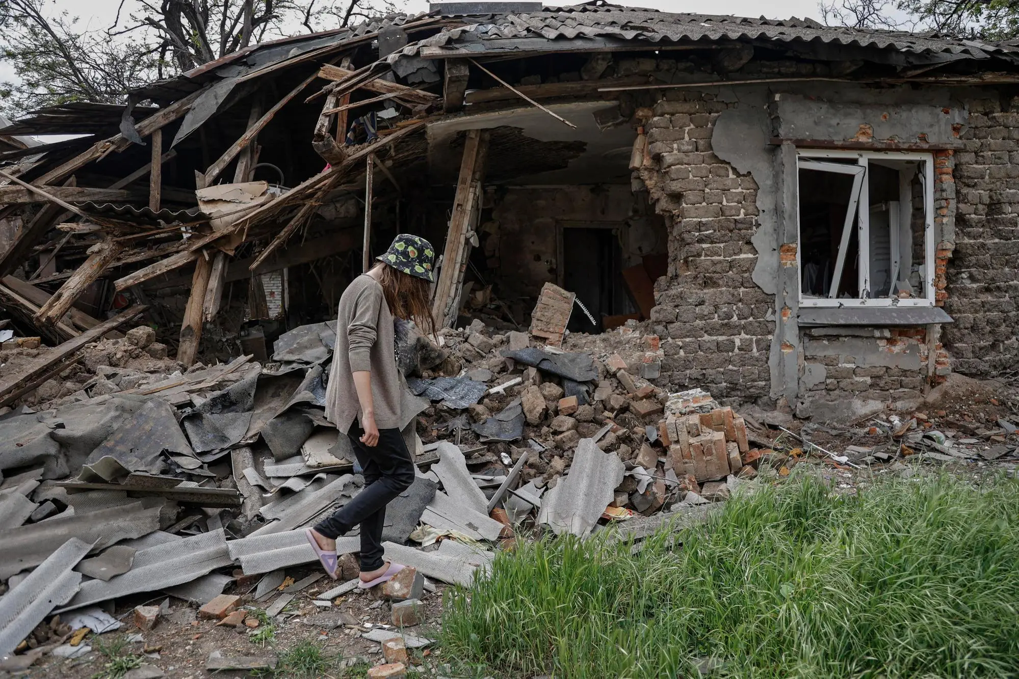 epa09965027 A woman walks past her destroyed house in Mariupol, Ukraine, 21 May 2022 (issued 22 May 2022). According to the Head of the self-proclaimed Donetsk People's Republic Denis Pushilin, 60 percent of the houses in Mariupol were destroyed, 20 percent of which cannot be rebuilt. The Chief spokesman of the Russian Defense Ministry, Major General Igor Konashenkov, said on 20 May that the long-besieged Azovstal steel plant in Mariupol was under full Russian army control. EPA/ALESSANDRO GUERRA