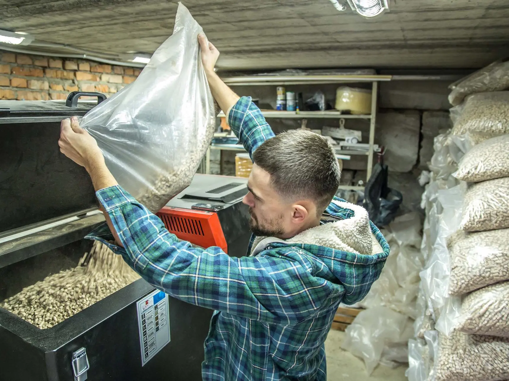 the man loads the pellets in the solid fuel boiler, working with biofuels, economical heating