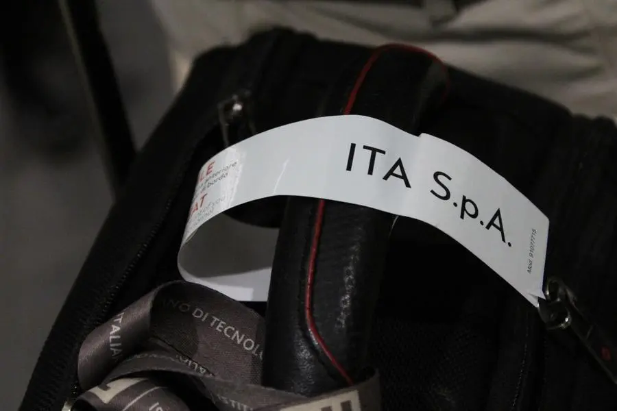 Il logo di Ita sui bagagli appena scaricati (Foto Ansa)