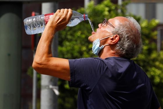 epaselect epa09412554 A tourist drinks water on a hot day in Cordoba, southern Spain, 13 August 2021. High temperatures were reached in most regions of Spain on a new heat wave that has sparked red alerts for warm temperatures. EPA/Salas
