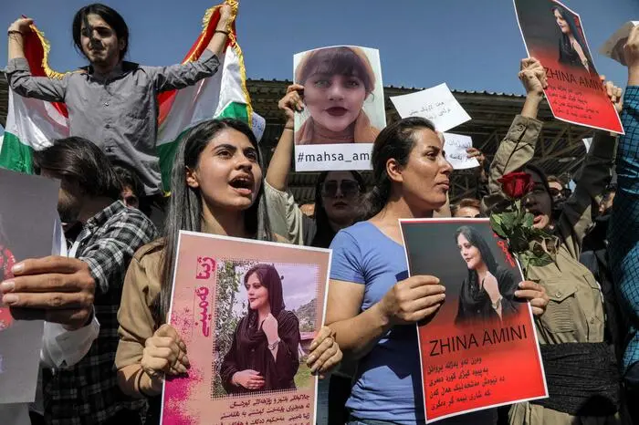 Women chant slogans and hold up signs depicting the image of 22-year-old Mahsa Amini, who died while in the custody of Iranian authorities, during a demonstration denouncing her death by Iraqi and Iranian Kurds outside the UN offices in Arbil, the capital of Iraq's autonomous Kurdistan region, on September 24, 2022. - Angry demonstrators have taken to the streets of major cities across Iran, including the capital Tehran, for eight straight nights since the death of 22-year-old Mahsa Amini. The Kurdish woman was pronounced dead after spending three days in a coma following her arrest by Iran's feared morality police for wearing the hijab headscarf in an "improper" way. (Photo by SAFIN HAMED / AFP)