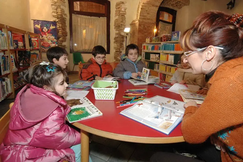 Bambini ascoltano le fiabe e si cimentano nella lettura in una biblioteca sarda