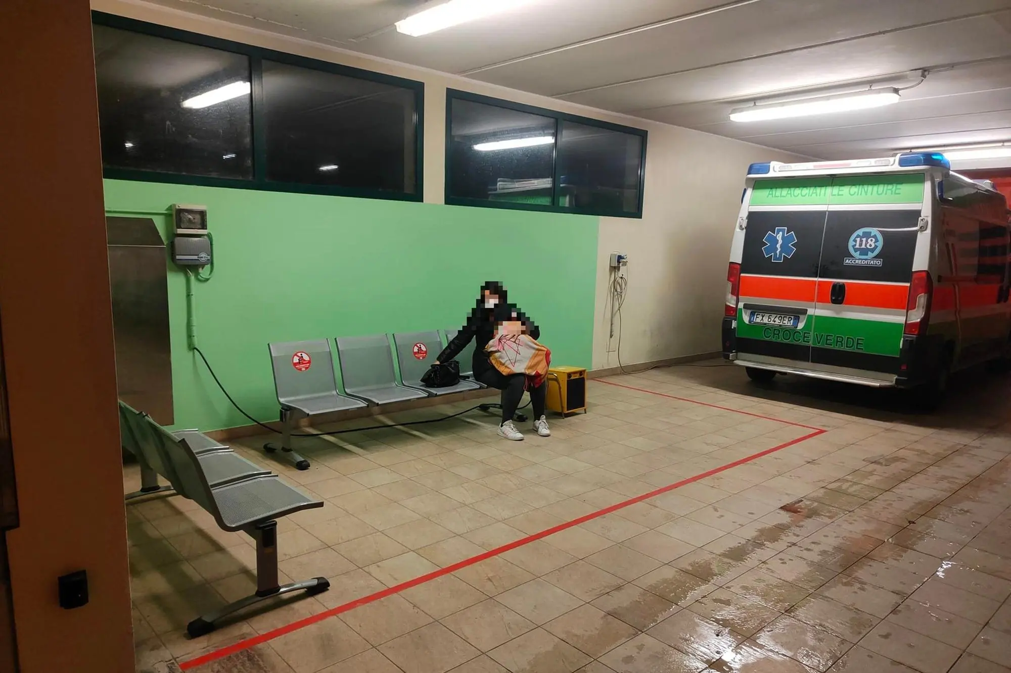 Una delle foto diffuse sui social mostra la donna seduta col figlioletto nel parcheggio delle ambulanze (foto Facebook)