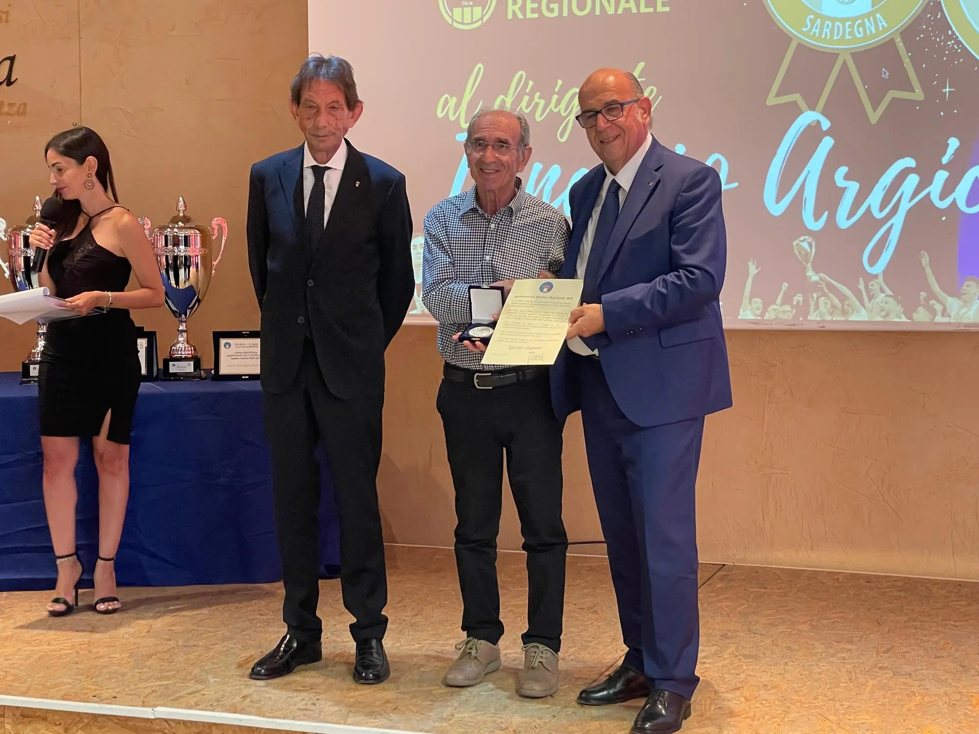 Gianni Cadoni (presidente del Cr Sardegna, a destra) e Bruno Perra (presidente del Coni Sardegna, a sinistra) consegnano la benemerenza a Ignazio Argiolas (foto Spignesi)