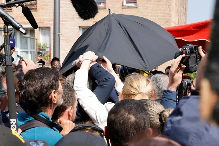 Un ombrello per proteggere Macron dal lancio di pomodori (Ansa)