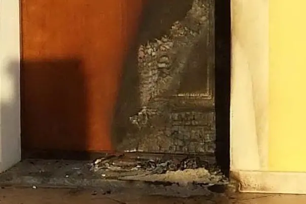 Il portone danneggiato dalle fiamme