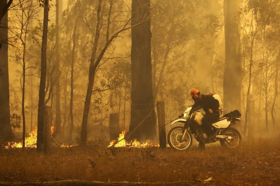 Un cittadino tenta di spegnere le fiamme (Ansa)