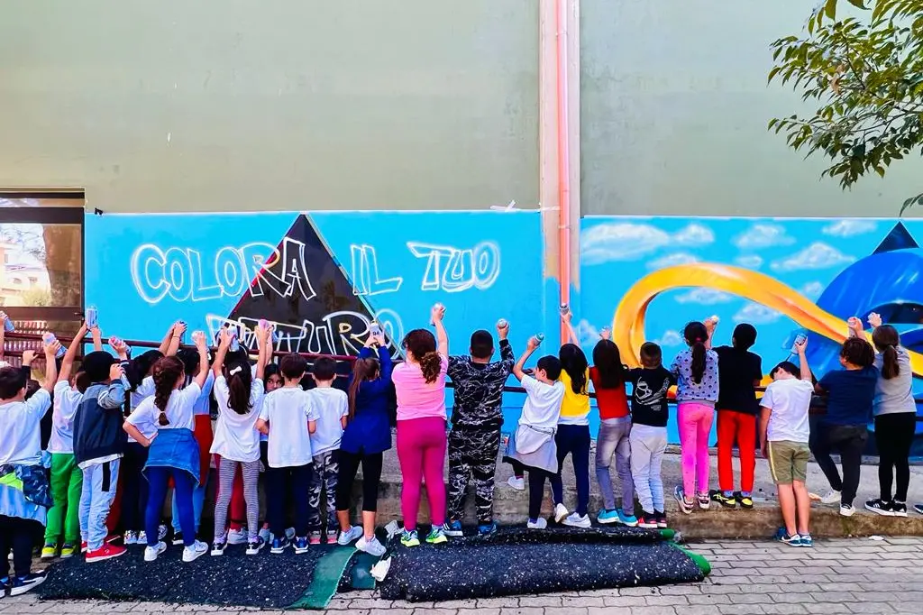 I ragazzi realizzano il murale a scuola (foto Serreli)