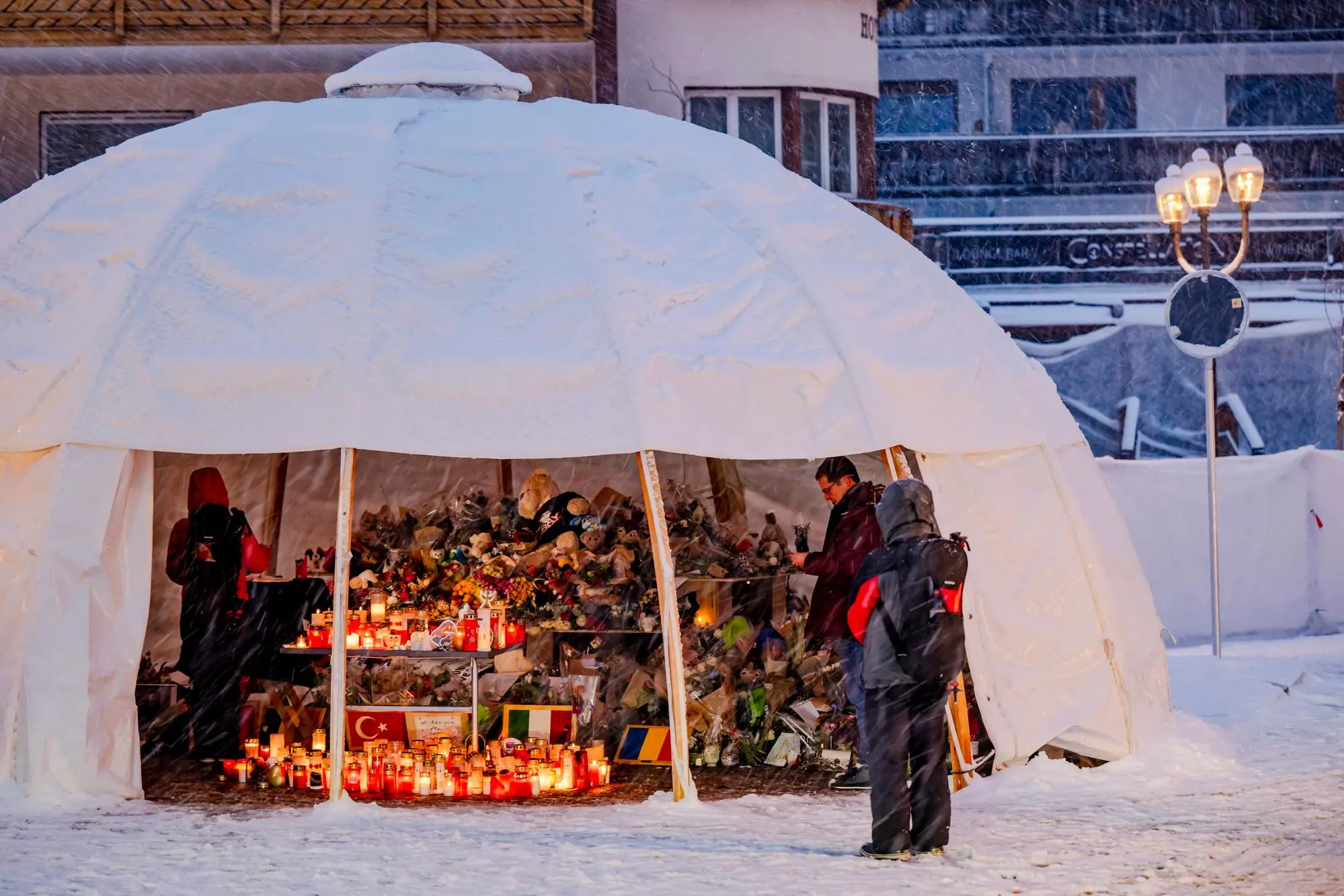 epa12636505 Mourners visit a tent sheltering flowers and candles left in tribute to the victims following a bar fire in Crans-Montana, Switzerland, 08 January 2026. Swiss authorities have confirmed 40 fatalities, mostly teenagers and young adults, and 116 severe injuries following a fire at the Le Constellation bar in Crans-Montana. The blaze occurred in the early hours of New Year's Day. EPA/JEAN-CHRISTOPHE BOTT