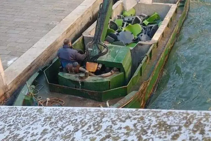 Il barchino intento a portare i banchi a rotelle in discarica (foto da facebook)
