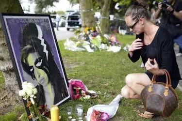 Una fan rende omaggio a Amy Winehouse di fronte a un suo ritratto