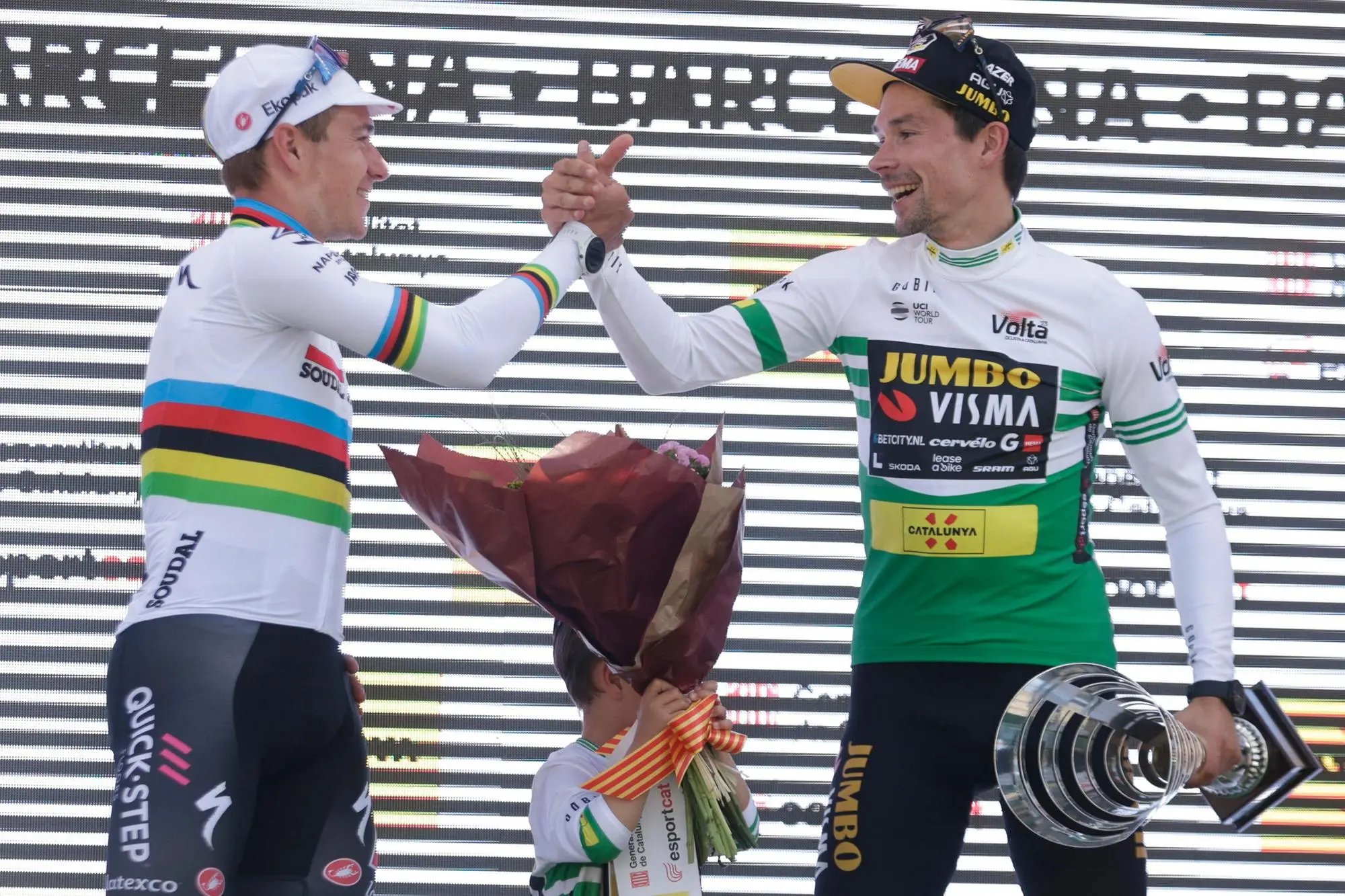 Stretta di mano tra l'iridato Remco Evenepoel e Primoz Roglic sul podio del Giro di Catalogna (Ansa)