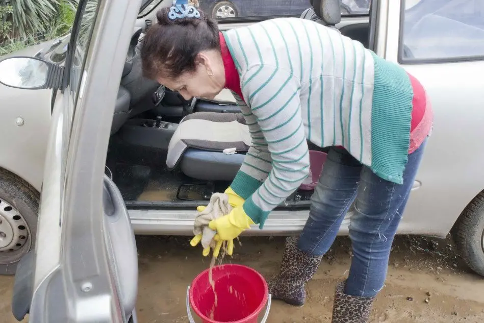 Una residente asciuga la sua macchina allagata (foto Murru)