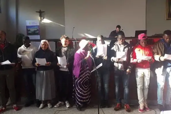 Un gruppo di immigrati intona un canto di benvenuto alla cerimonia con l'arcivescovo Arrigo Miglio