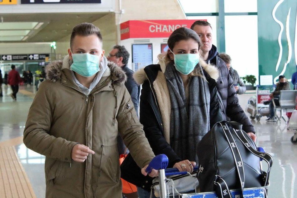 Viaggiatori in aeroporto con le mascherine (foto L'Unione Sarda)