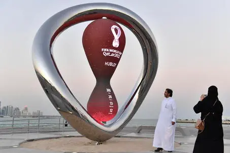 epa09603372 People pose in front of the clock counting down to the first match of the FIFA World Cup 2022 at Doha Corniche in Doha, Qatar, 25 November 2021. The FIFA World Cup 2022, the first to be held in the Middle East, will take place in Qatar from 21 November to 18 December 2022. EPA/NOUSHAD THEKKAYIL