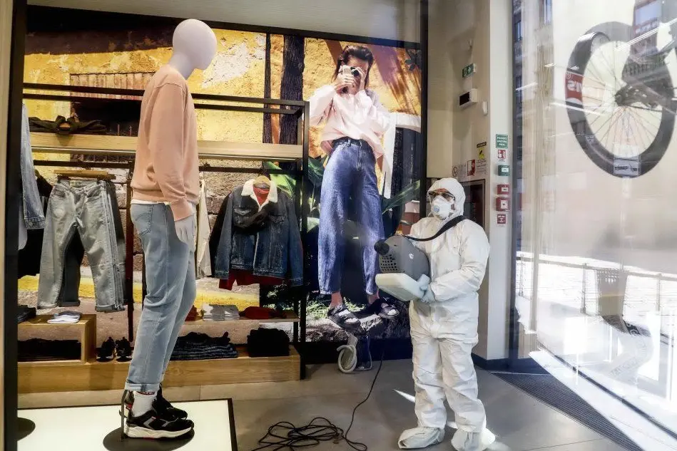 Sanificazione in un negozio di Milano (Ansa)