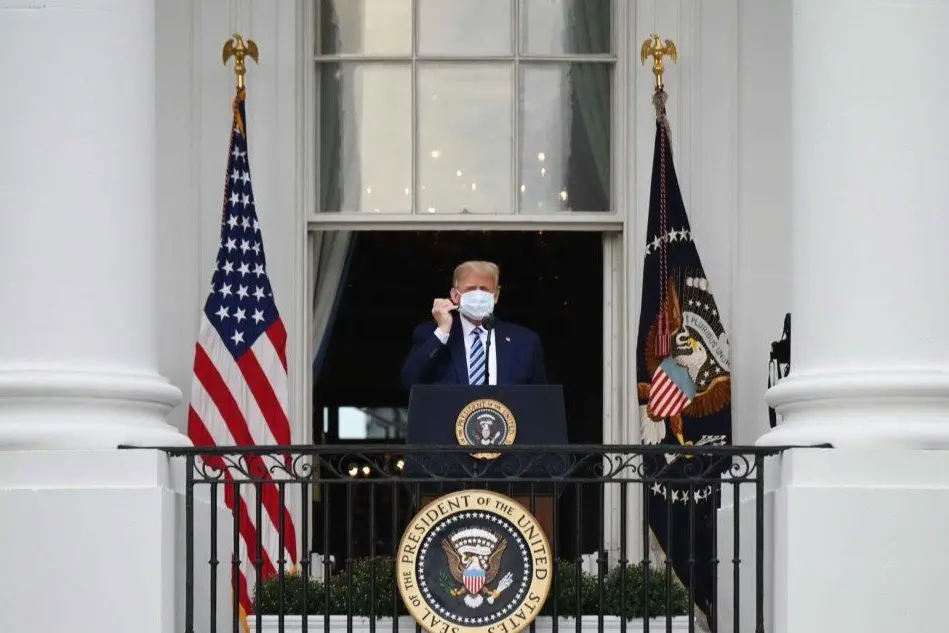 Donald Trump mentre si toglie la mascherina (Ansa - Scott)