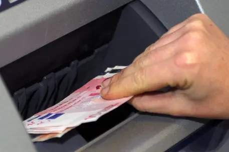 Un prelievo di denaro contante a uno sportello bancomat (Ansa)
