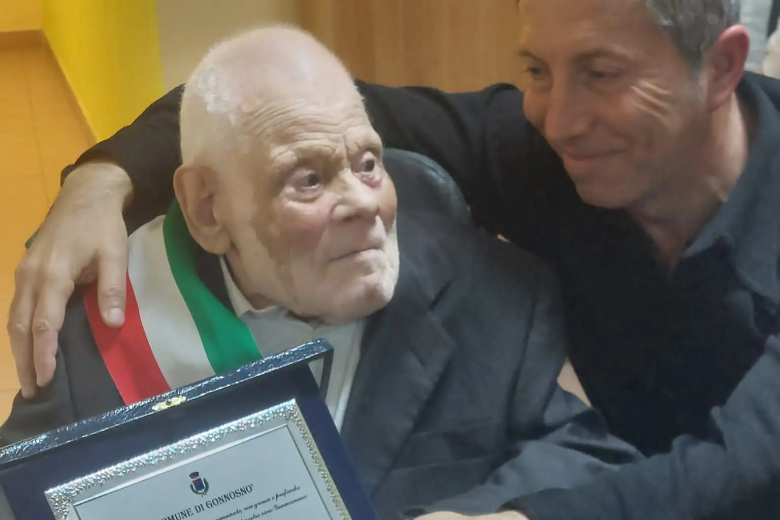 Il momento della consegna della targa da parte del sindaco Ignazio Peis al centenario Giovannino Farris (foto concessa)