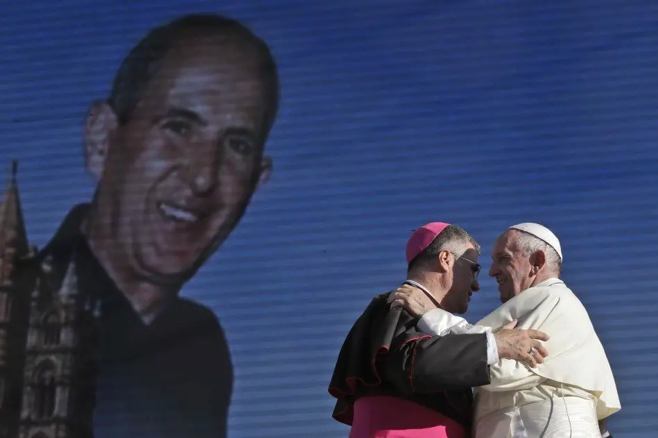 Papa Francesco e l'arcivescovo di Palermo Corrado Lorefice si abbracciano a Palermo davanti al ritratto di don Puglisi (Ansa)