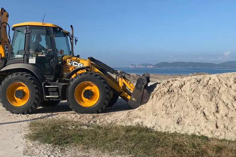 Mezzi al lavoro per ridistribuire la sabbia ad Alghero (foto Fiori)