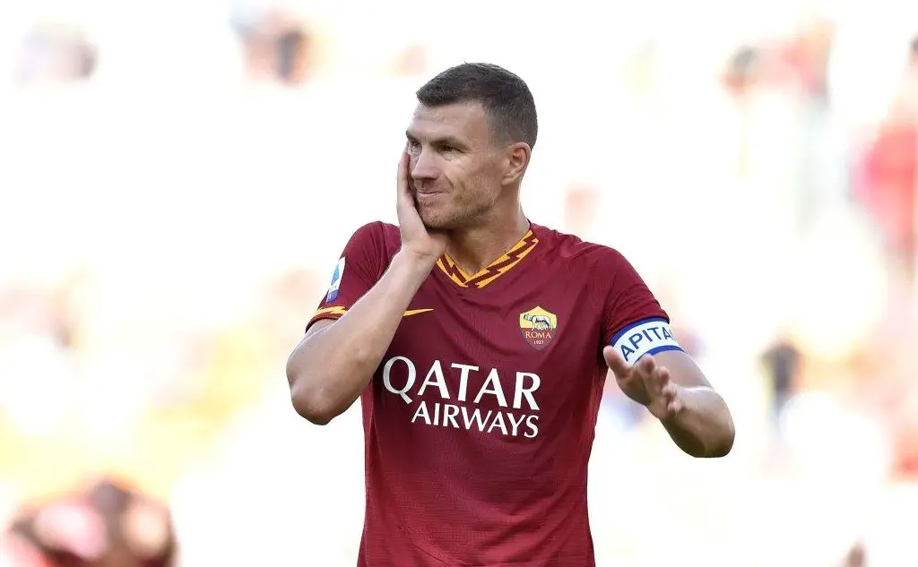 Dzeko si tocca il volto dopo un colpo ricevuto (Foto Ansa, Cagliari Calcio e As Roma)
