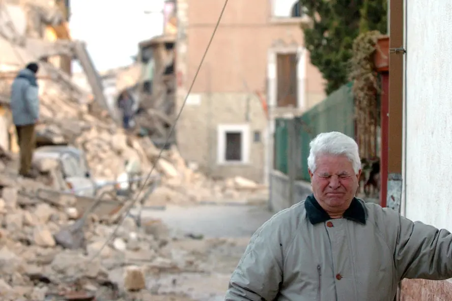 La disperazione di un uomo anziano tra le macerie di un edificio crollato in seguito al sisma ad Onna