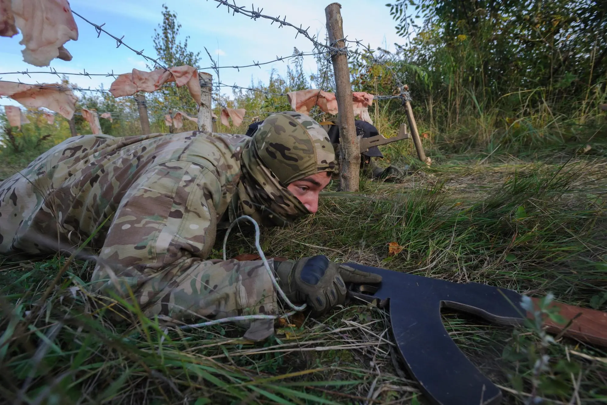 epaselect epa10204506 A civilian holding a wooden replica of a rifle crawls under barbed wire during military training organized by the Ukrainian political organization Right Sector, in the Lviv region, western Ukraine, 24 September 2022. Forty-five civilians took part in a three-day military training in the Lviv region. Russian troops entered Ukraine on 24 February 2022 starting a conflict that has provoked destruction and a humanitarian crisis. EPA/MYKOLA TYS